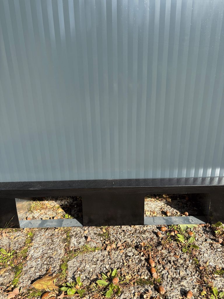 Forklift slots at the base of a portable shower unit for camping.